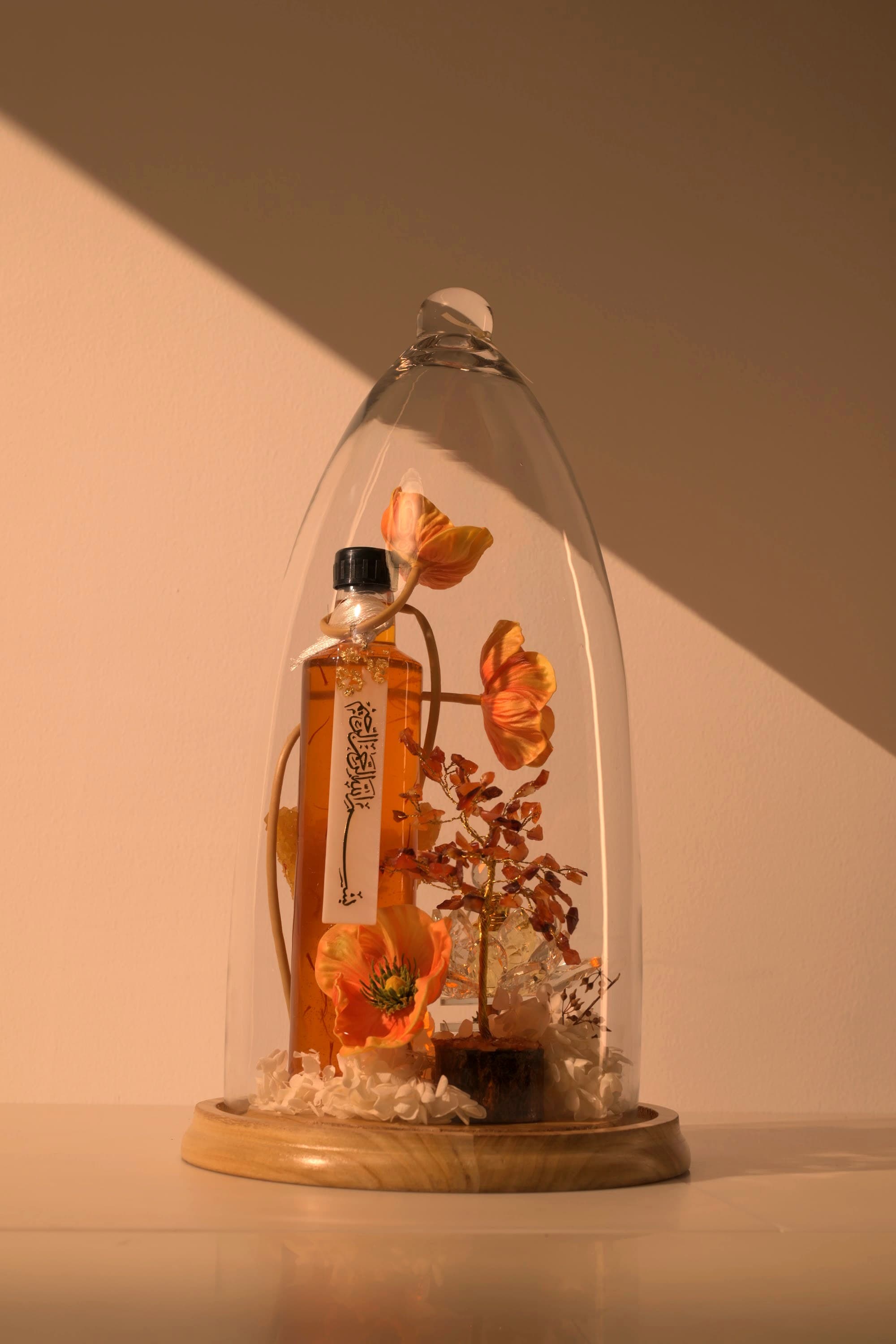A Bare & Brown signature glass dome arrangement with saffron, edible florals and fresh confections in warm natural light