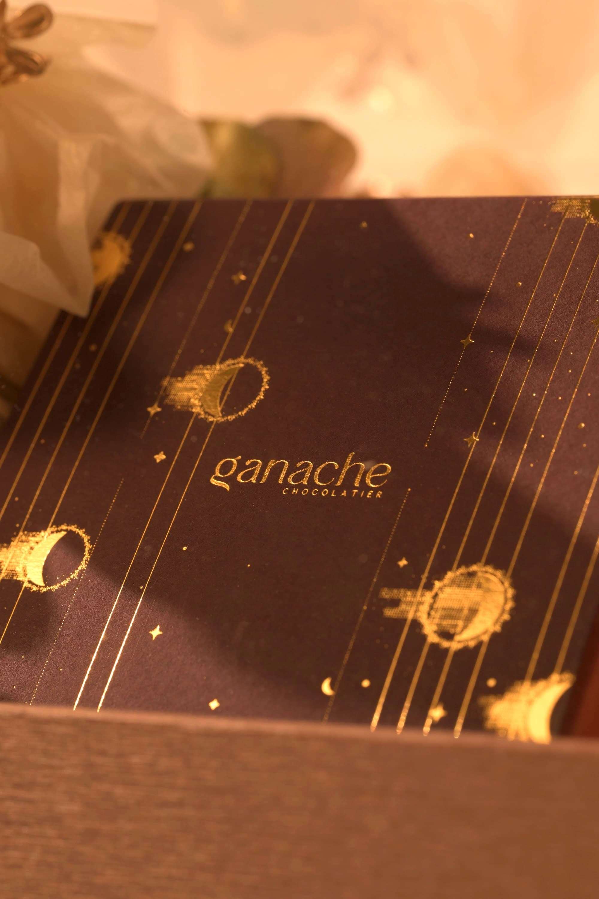 A gold-detailed ganache box being composed inside a bespoke Bare & Brown gift