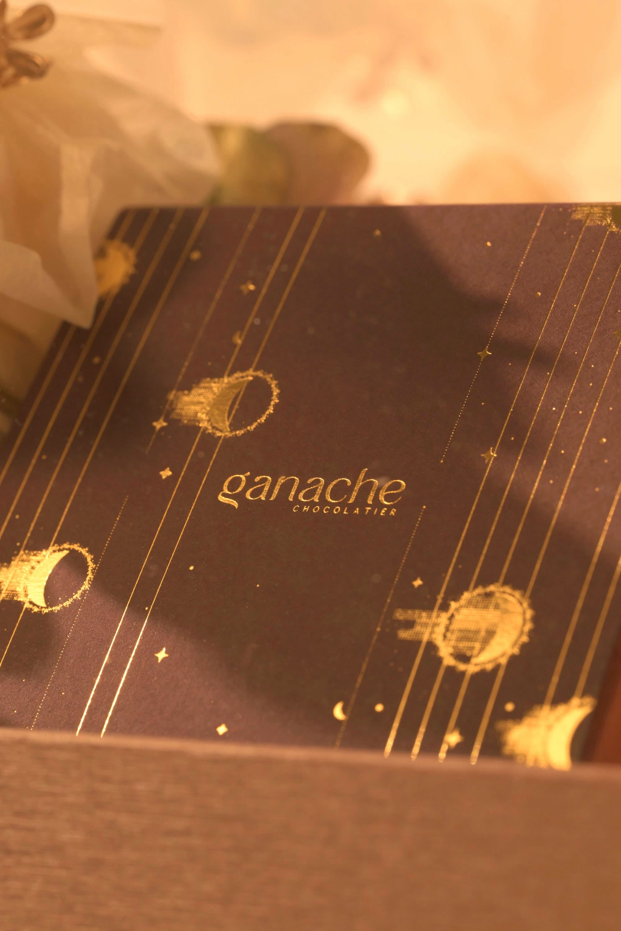 A gold-detailed ganache box being composed inside a bespoke Bare & Brown gift