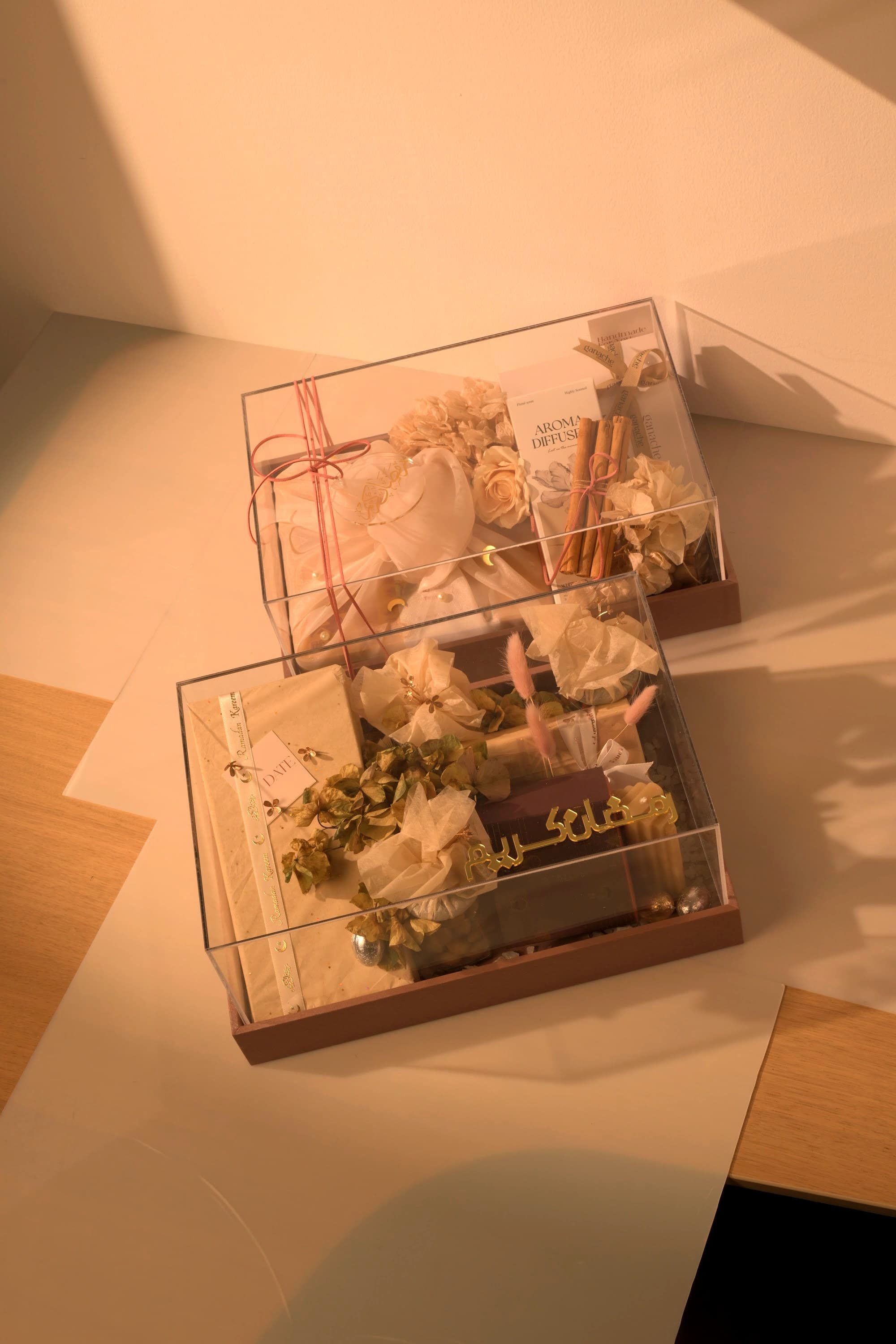Two clear Bare & Brown gift boxes with curated treats, florals and a diffuser