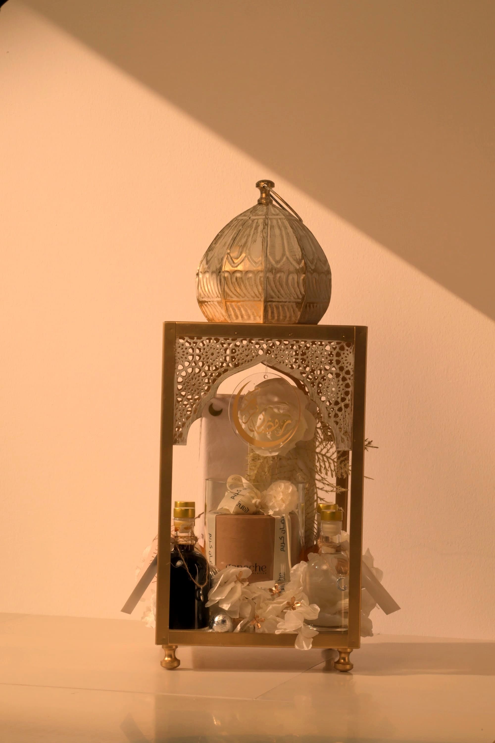 A bespoke Bare & Brown gift — a domed gold lantern arrangement with saffron, florals and chocolates, in warm natural light